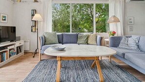 Ein modernes Wohnzimmer mit einem grauen Sofa, einem runden Couchtisch und einem Bücherregal.