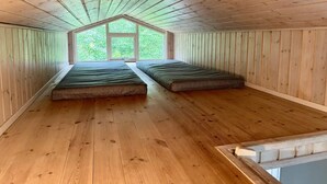 A room with wooden walls and a sloped ceiling, featuring two beds and a large window. - 5 Star Holiday Home in Eskebjerg (Eskebjerg)