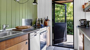 Une cuisine compacte équipée d’un évier, d’une cuisinière et d’une fenêtre donnant sur un jardin.