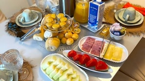 Monipuolinen aamiaisbuffet, jossa on tarjolla erilaisia hedelmiä, leivonnaisia ja juomia.