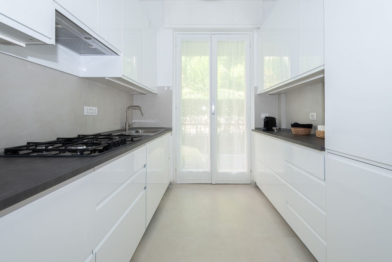 Una cucina moderna con pensili bianchi, un piano di lavoro nero e un piano cottura a gas.