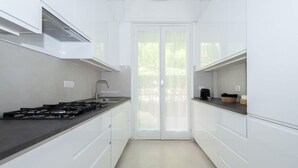 Uma cozinha moderna com armários brancos, bancada preta e fogão a gás.