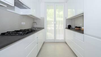 Una cucina moderna con pensili bianchi, un piano di lavoro nero e un piano cottura a gas.