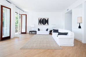 A spacious living room with a large window, a white sofa, a coffee table, and a rug. - Beautiful Lake View (Como)