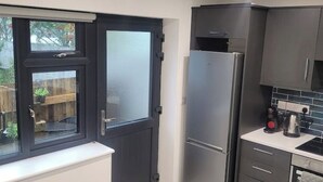 A kitchen with a refrigerator, cabinets, and a window with a view of the outside.
