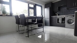 A modern kitchen with a dining area, large windows, and a washing machine.