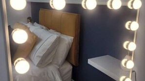 A bedroom with a bed, a headboard, and a wall-mounted shelf.