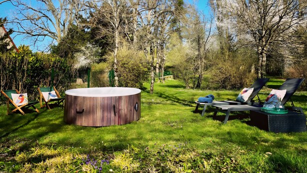 A circular wooden structure in a grassy outdoor area with lounge chairs and easels.