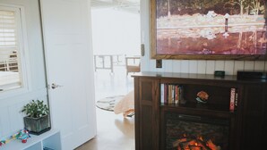 Een kamer met een open haard, een televisie erboven en een boekenplank vol boeken.