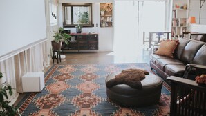 Een woonkamer met een bank, een poef en een vloerkleed.