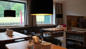 A cozy restaurant with outdoor seating, a coffee station, and a view of a wooden deck.