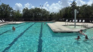 A swimming pool with multiple lanes, a lifeguard chair, and a fenced area with lounge chairs.