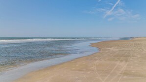 Une plage avec un ciel dégagé et des vagues sur l’océan.