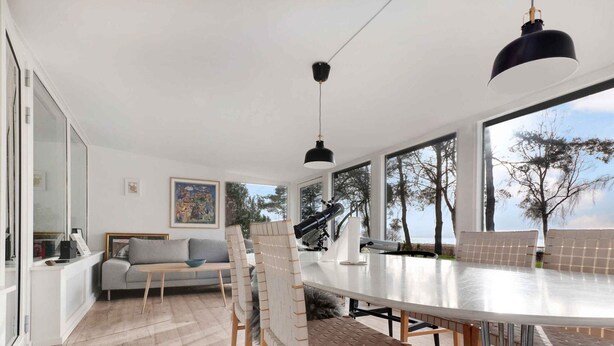 A modern living room with a large dining table, a sofa, and a telescope. - 5 Star Holiday Home in Vig (Vig)