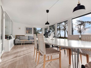 A modern living room with a large dining table, a sofa, and a telescope. - 5 Star Holiday Home in Vig (Vig)
