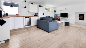A modern living space with a kitchen, dining area, and a seating area with a sofa and coffee table. - 5 Star Holiday Home in Vig (Vig)