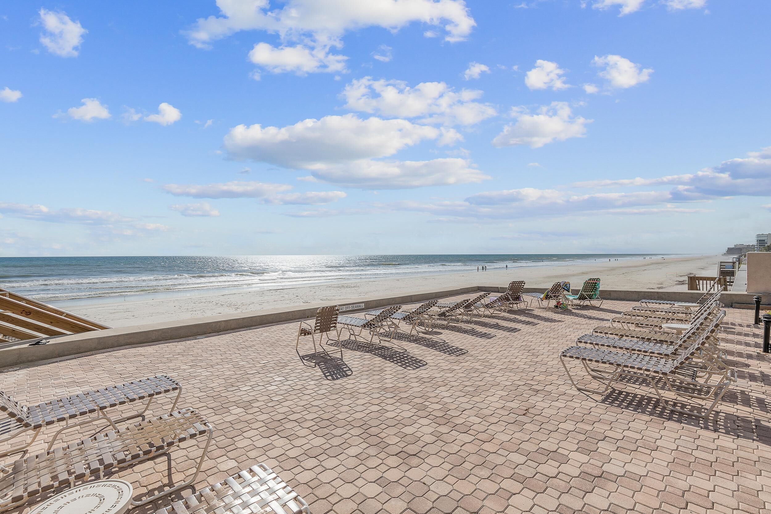 Eine Terrasse direkt am Strand mit Liegestühlen und Blick auf das Meer.