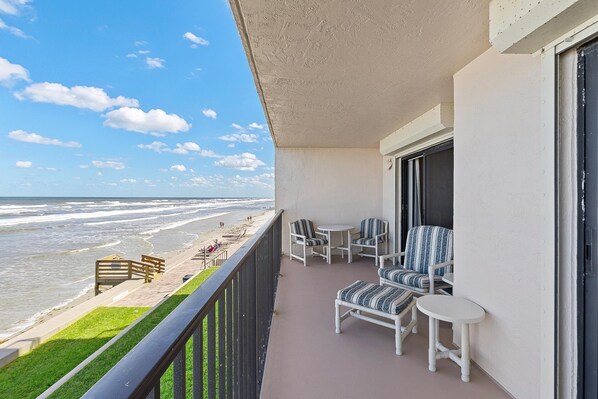 A balcony with a view of the beach, featuring a small table and chairs. - Hacienda del Sol II 213 (New Smyrna Beach)