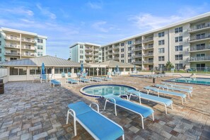 A hotel with multiple balconies, outdoor pools, and lounge chairs. - Sea Coast Gardens II 501 (New Smyrna Beach)