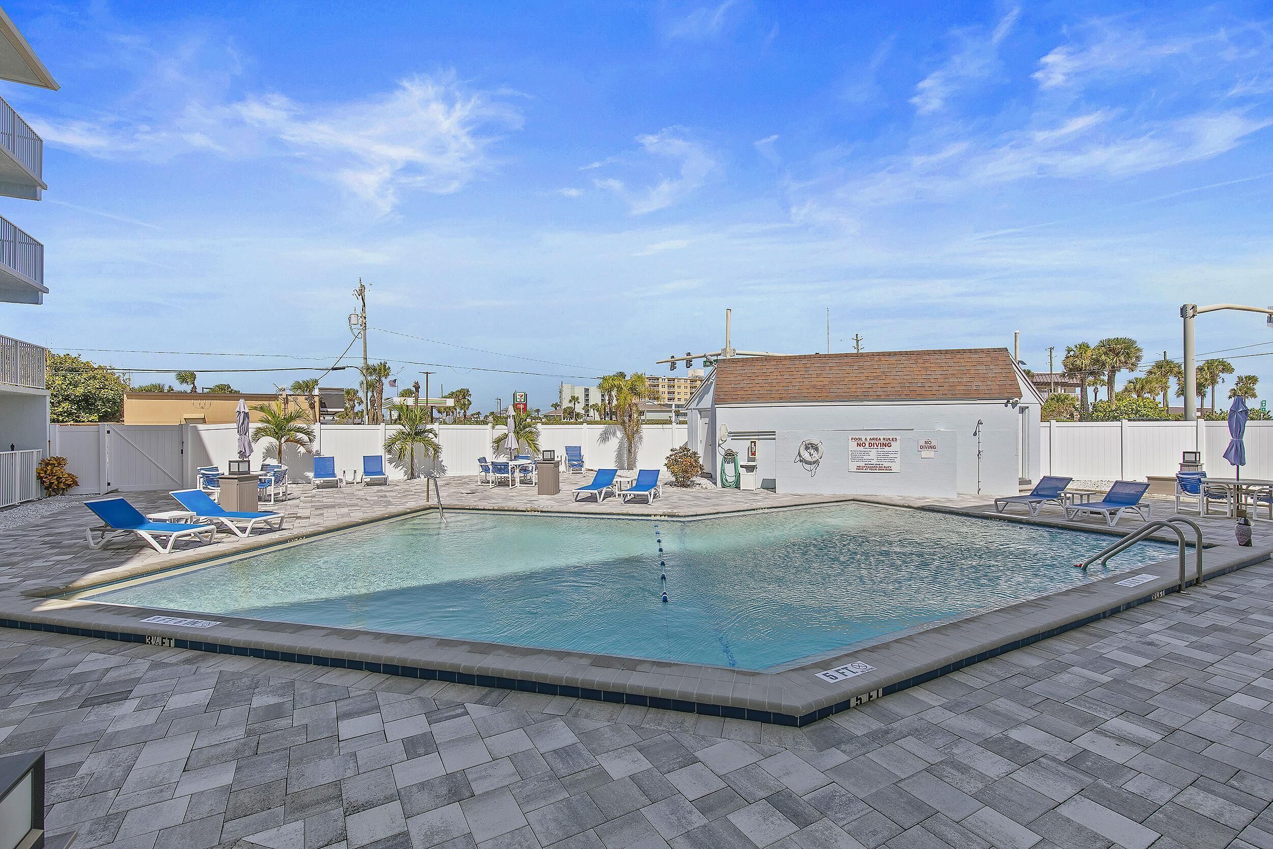 A swimming pool with lounge chairs and a lifeguard stand.