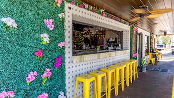 En restaurant med en grøn væg dekoreret med blomster, en disk med barstole og en loftsvifte.