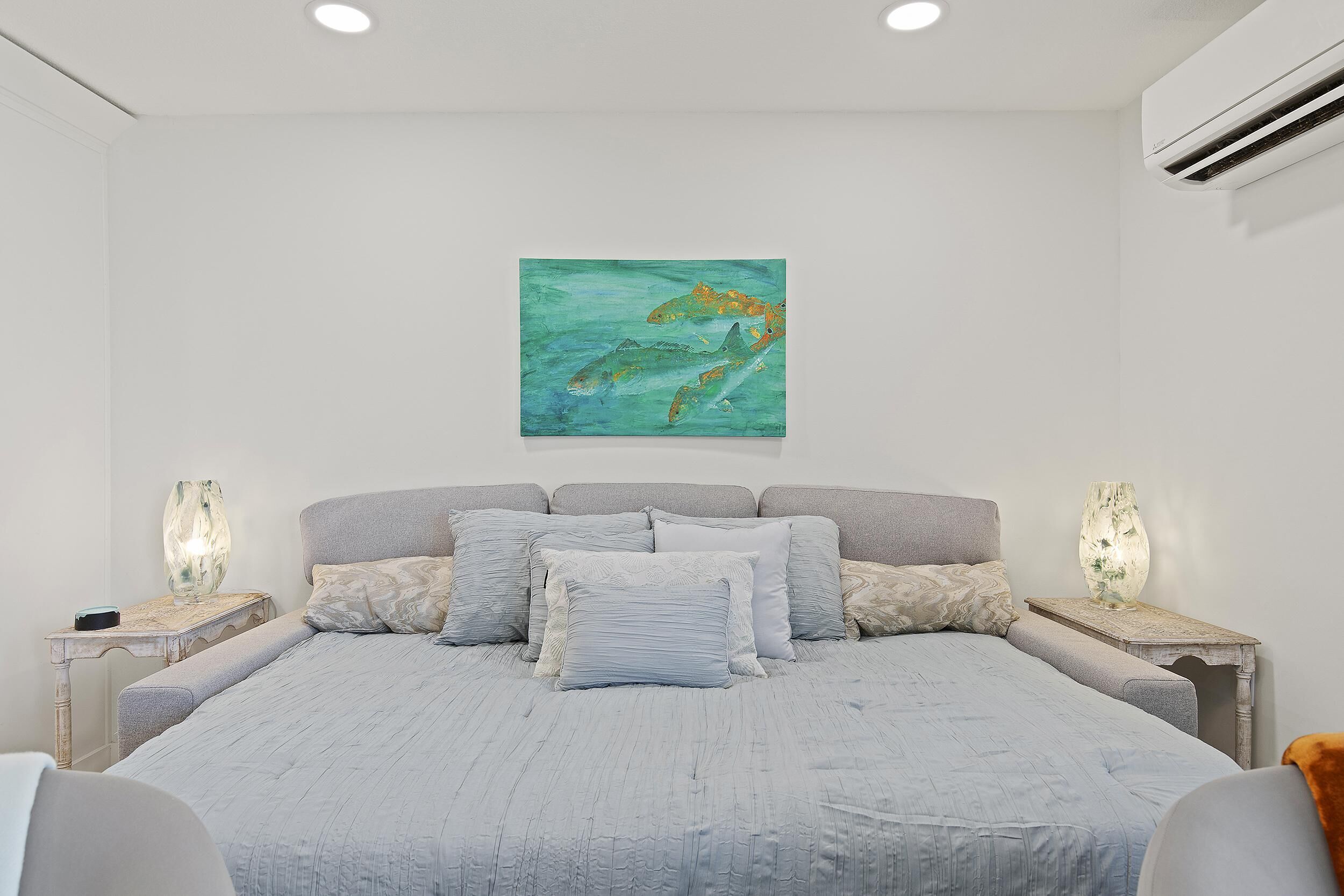 Un dormitorio con cama, mesitas de noche y aire acondicionado instalado en la pared.