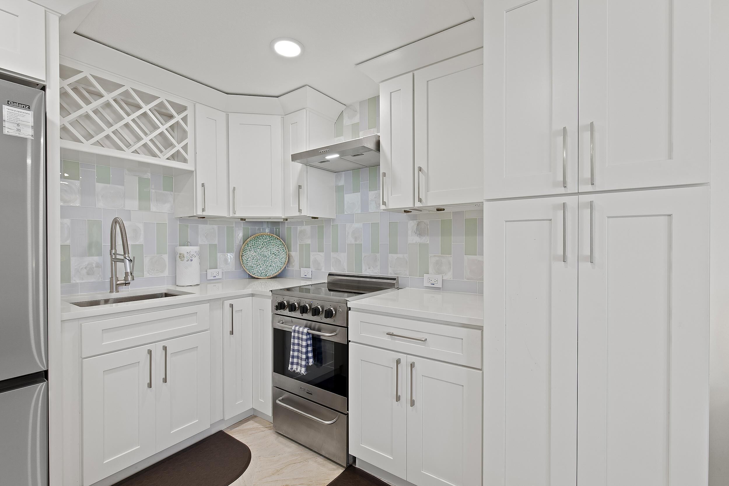 A modern kitchen with white cabinetry, a stainless steel stove, and a built-in oven.