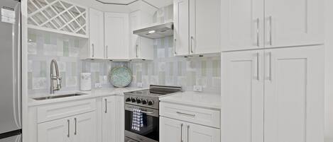 A modern kitchen with white cabinetry, a stainless steel stove, and a built-in oven.