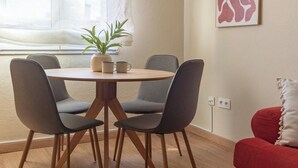 Un comedor con una mesa redonda, cuatro sillas, una planta en maceta y un sofá rojo.