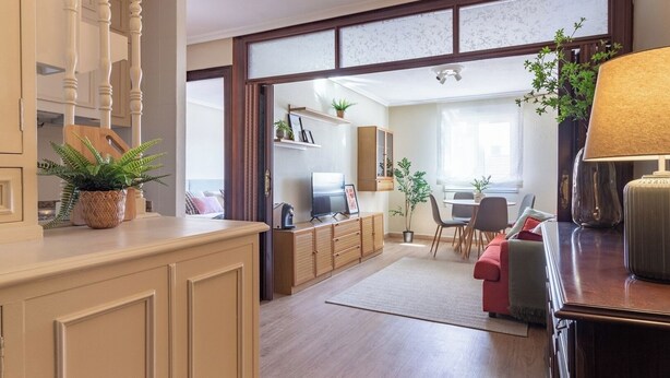Un amplio salón con un aparador de madera, un televisor y una mesa de comedor con sillas.