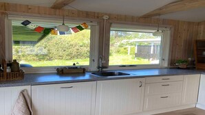 A kitchen with white cabinets, a granite countertop, a double sink, and a window with a view of greenery. - 5 Star Holiday Home in Hundested (Hundested)