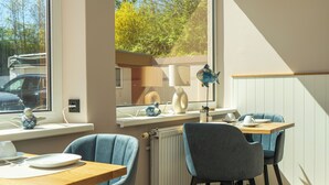 A dining area with a table, chairs, and a window overlooking a parking area. - Hotel Seebrise Grömitz (Groemitz)