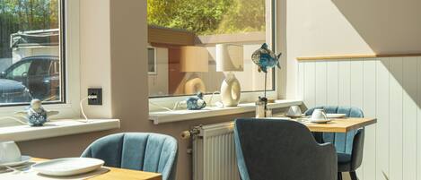 A dining area with a table, chairs, and a window overlooking a parking area.