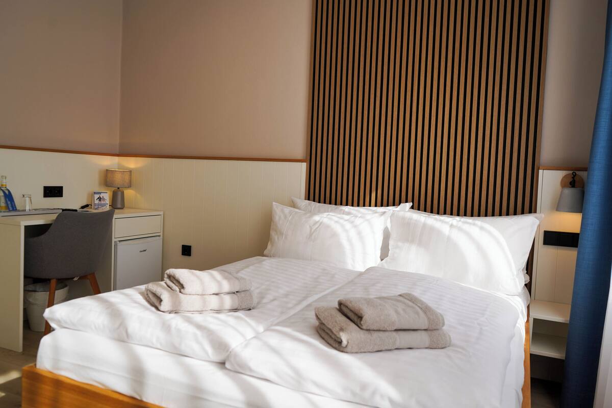 Una camera d'albergo con un letto, una scrivania, una sedia e un muro con linee verticali.