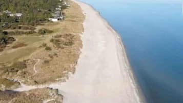 Paisagem costeira com uma praia e uma estrada serpenteando pela costa.