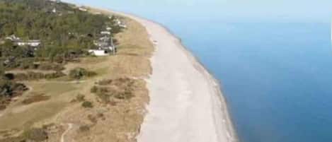 A coastal landscape with a beach and a road curving along the shore.