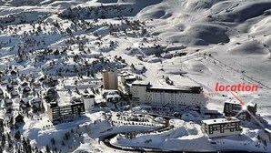 Une région montagneuse enneigée comprenant une station de ski, avec des bâtiments et des pistes de ski.