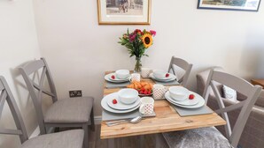 A dining table set with plates, cups, and a croissant, surrounded by chairs. - Farriers Yard (Whitby)