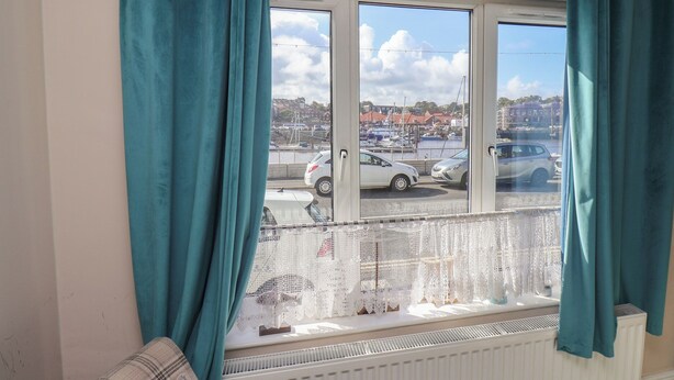 A room with a view of a marina, a white radiator, and teal curtains. - Farriers Yard (Whitby)