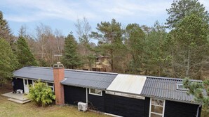 A single-story house with a metal roof, a brick chimney, and a small porch. - 5 Star Holiday Home in Nykobing Sj (Nykobing Sjaelland)