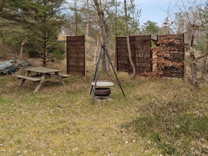 A rustic outdoor setting with a wooden picnic table, a metal pot, and a clothesline with hanging items.