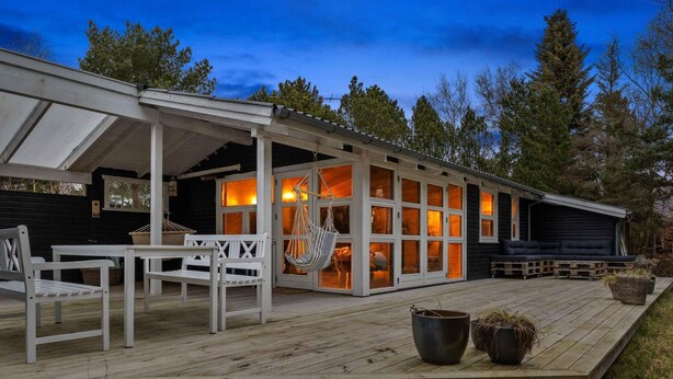A wooden deck with white furniture, a hanging chair, and a sofa. - 5 Star Holiday Home in Nykobing Sj (Nykobing Sjaelland)