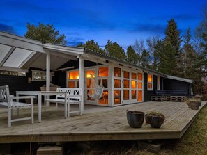 Eine Holzterrasse mit weißer Möbelgruppe, einer Hängesessel und einer Couch.