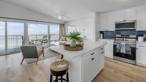 Una cocina moderna con armarios blancos, horno de acero inoxidable y una isla grande con un centro de plantas.