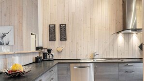 A modern kitchen with a wooden wall, a coffee machine, a dishwasher, and a sink. - 5 Star Holiday Home in Juelsminde (Horsens)