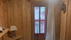 A wooden room with a bed, a window with curtains, a lamp, and a shelf. - Chalet 'Saint Roch' with Mountain View, Private Terrace and Wi-Fi (Val-Cenis)