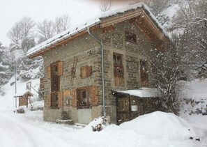 A stone building with multiple windows and a snow-covered roof.