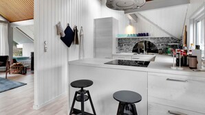 A modern kitchen with a central island, white cabinetry, and a stone backsplash.