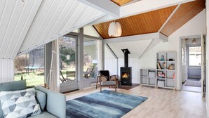 A spacious living area with a large window, a built-in wood stove, and a cozy seating area.