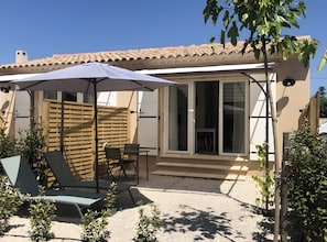A patio with a table and chairs, a wooden fence, and a covered area with an umbrella. - Studio "La Fourmi" with Mountain View, Wi-Fi and Air Conditioning (Taillades)